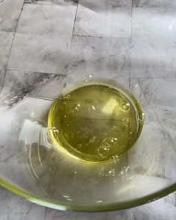 Una ciotola di vetro piena di un liquido giallo su un tavolo.