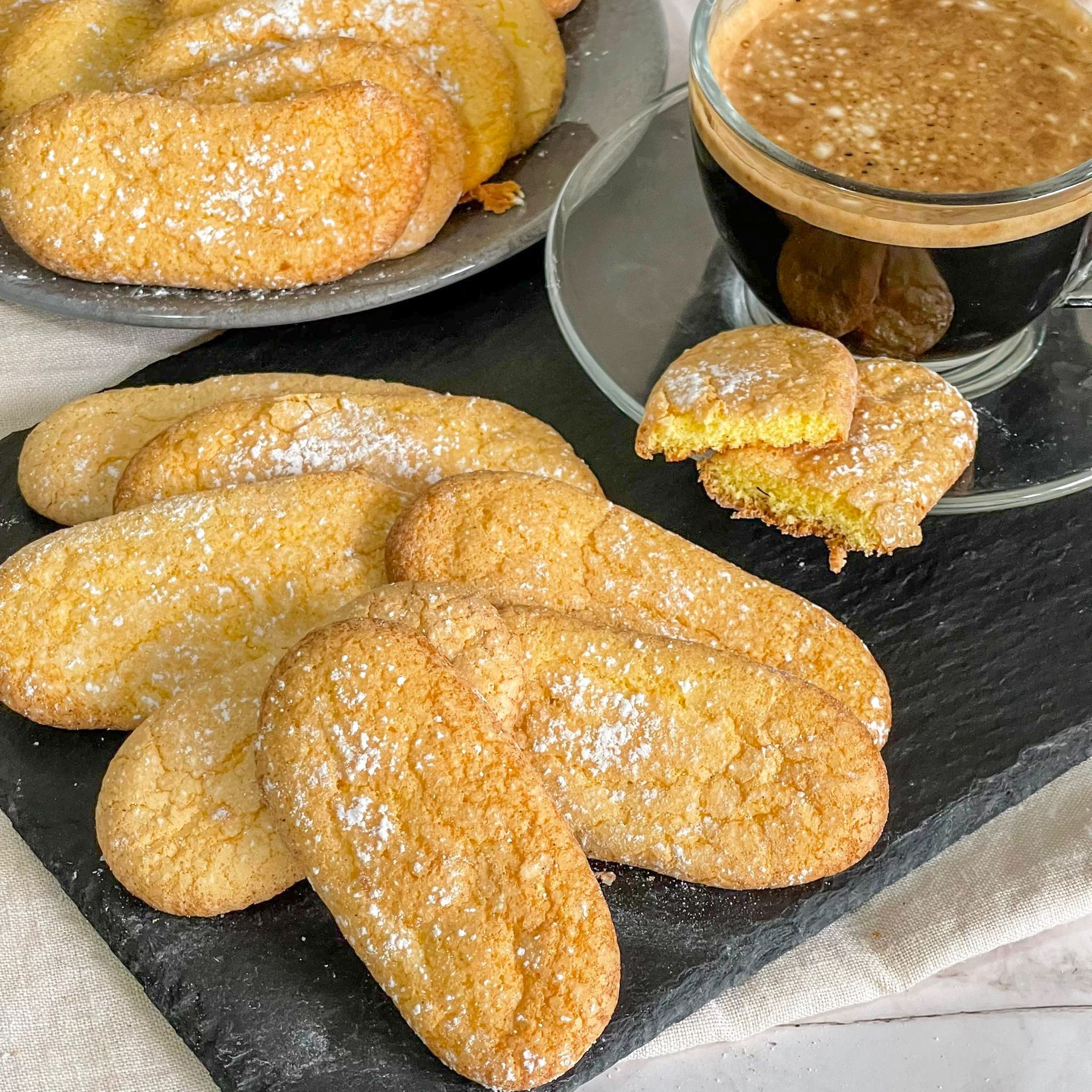 Un piatto di biscotti e una tazza di caffè su un tagliere.