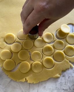 Una persona sta tagliando dei cerchi dall'impasto con un tagliabiscotti