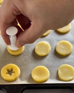 Una persona sta usando un tagliabiscotti su una teglia di biscotti