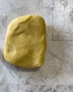 Una palla di pasta gialla è appoggiata su una superficie di marmo.