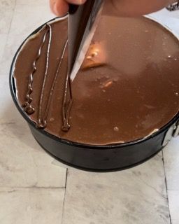 Una persona sta glassando una torta al cioccolato con una sac à poche