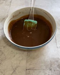 Una ciotola di liquido marrone con una spatola dentro