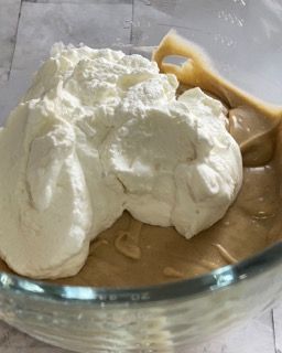 Una ciotola di vetro piena di burro di arachidi e panna montata.