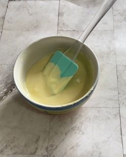 Una ciotola di liquido giallo con una spatola dentro