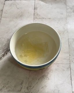 Una ciotola piena di liquido è appoggiata su un pavimento piastrellato.