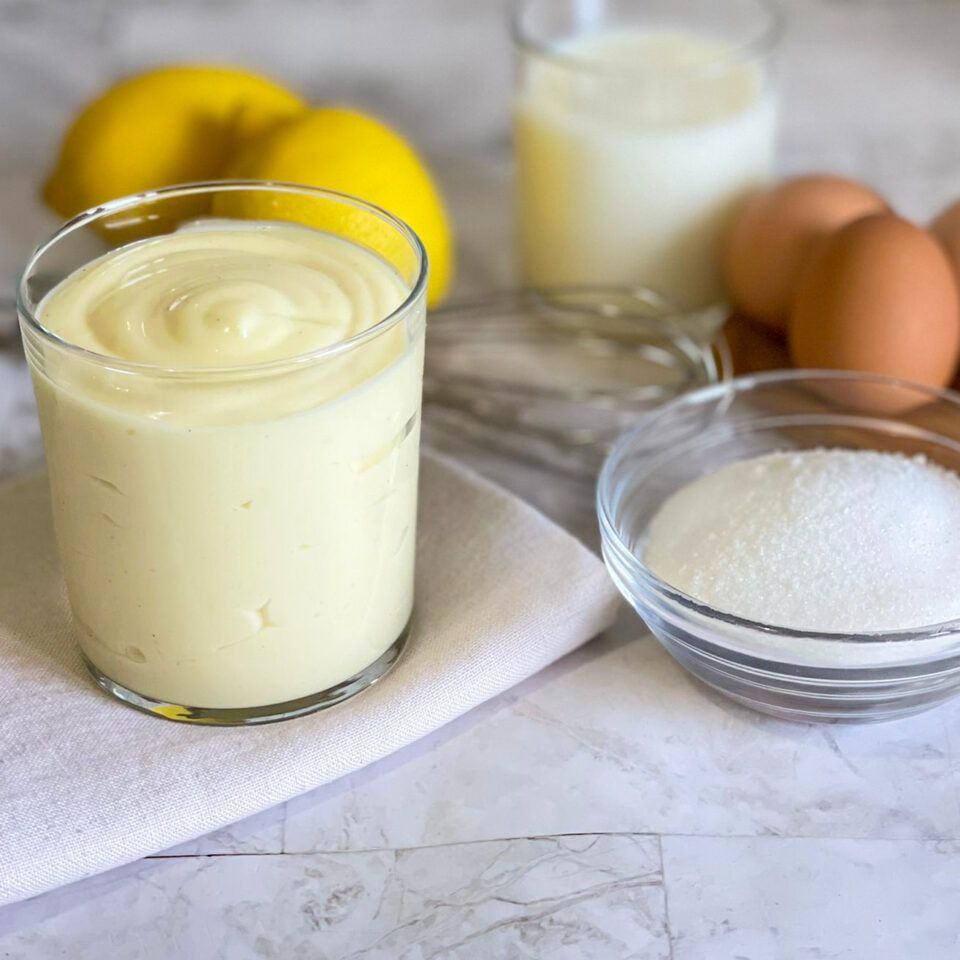 Un bicchiere di yogurt accanto a una ciotola di zucchero e uova