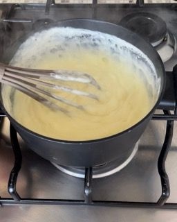 Una pentola di zuppa viene mescolata con una frusta sul fornello.