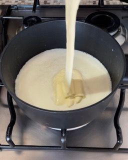 Una salsa viene versata in una pentola sul fornello