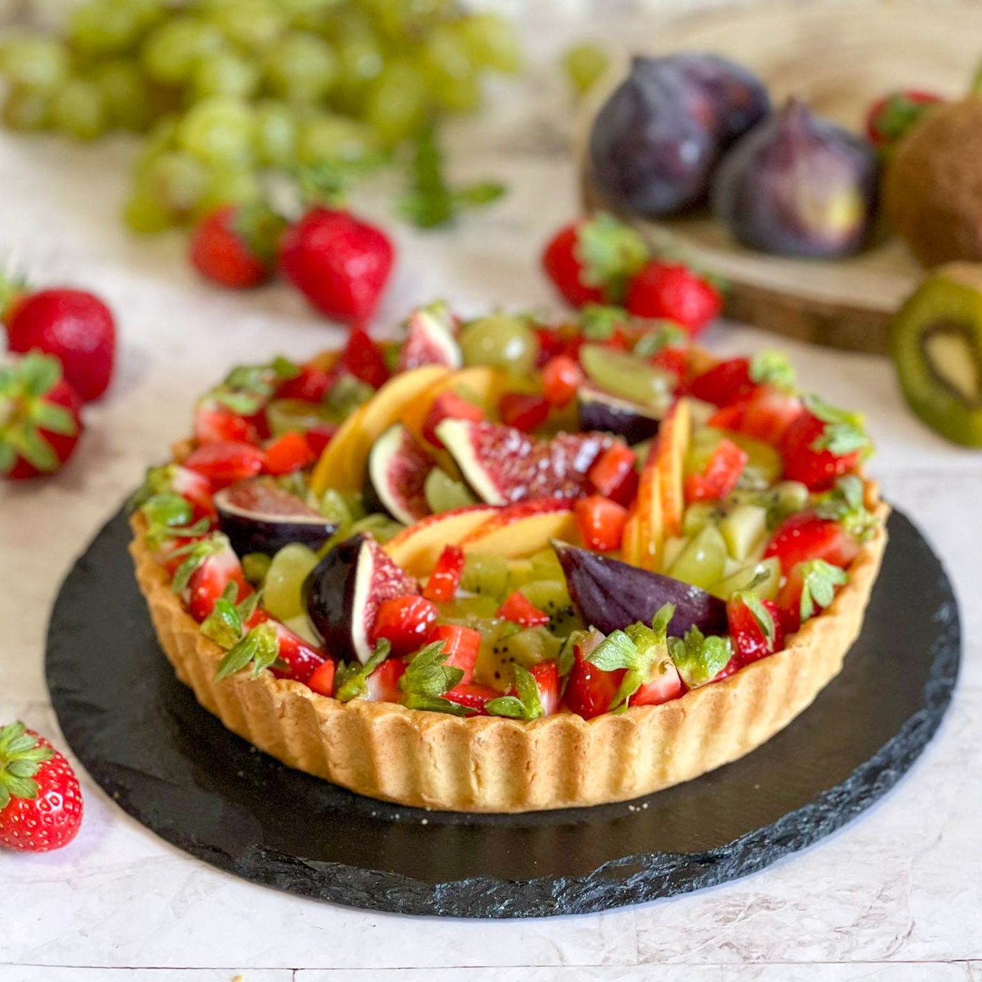 Una crostata di frutta è appoggiata su un piatto nero su un tavolo.