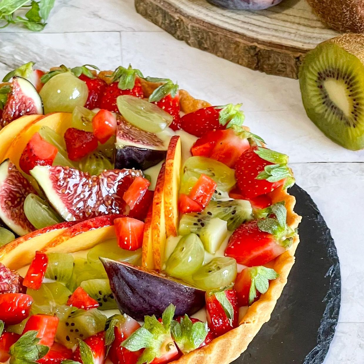 Una crostata di frutta con fragole, uva e kiwi sopra