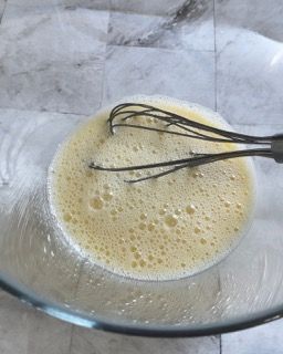 Una frusta è in una ciotola di liquido schiumoso.