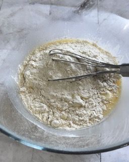 Una ciotola di farina con una frusta dentro.