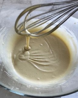 Si usa una frusta per mescolare un liquido in una ciotola di vetro.