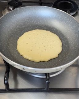 Un pancake sta cuocendo in una padella sul fornello