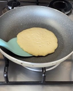 Un pancake viene cucinato in una padella con una spatola
