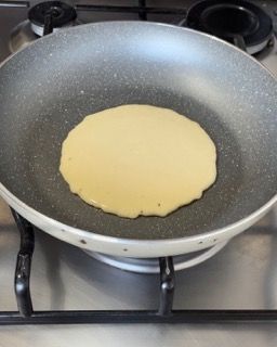 Un pancake sta cuocendo in una padella sul fornello