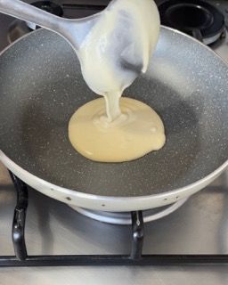 Un cucchiaio versa del liquido in una padella