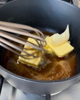 Si usa una frusta per mescolare il burro in una padella.