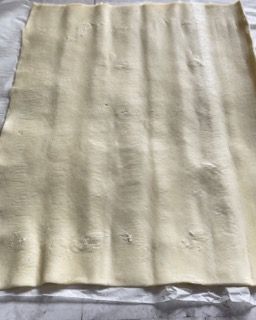 Un pezzo di pasta sfoglia è appoggiato su un tavolo.