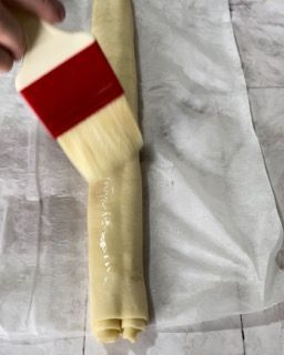 Una persona tiene un pennello sopra un pezzo di cibo