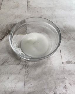 Una ciotola di vetro piena di liquido bianco è appoggiata su un pavimento piastrellato.