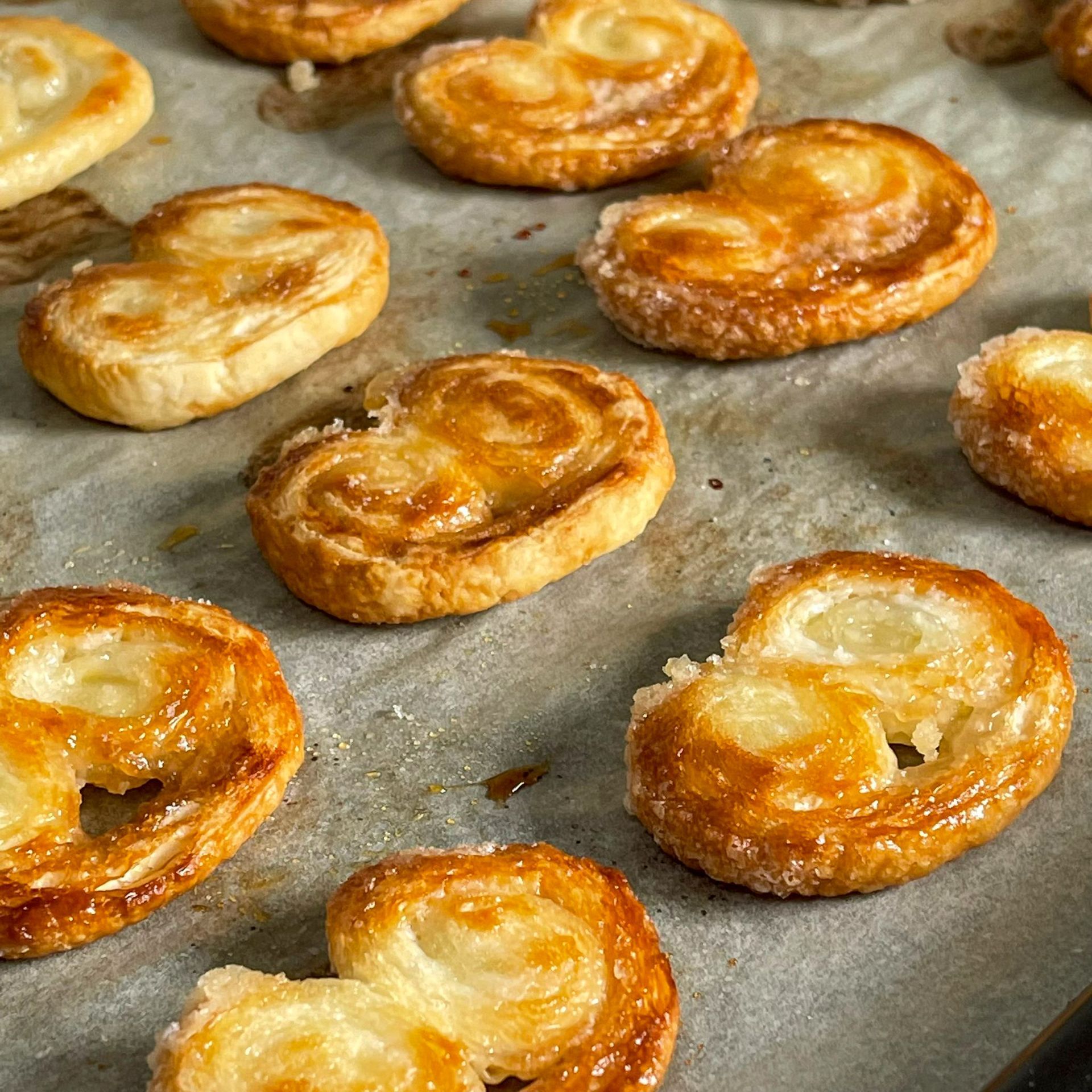 Un mucchio di pasticcini a forma di cuore sono sistemati su una teglia da forno.