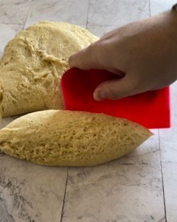 Una persona tiene una spatola rossa sopra un pezzo di pasta