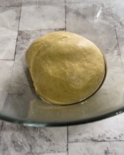 Una palla di pasta è posta in una ciotola di vetro.
