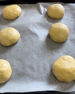 Sei palline di pasta sono appoggiate su un pezzo di carta oleata