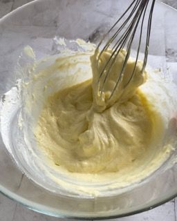 Una persona sta sbattendo un liquido giallo in una ciotola di vetro