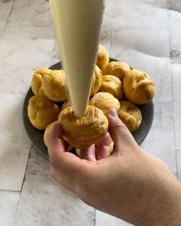 Una persona tiene in mano un dolce davanti a un piatto di dolci