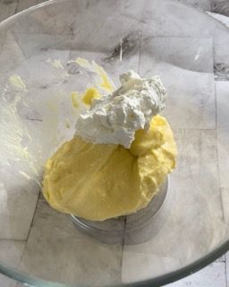 Una ciotola di vetro piena di salsa gialla e panna montata.