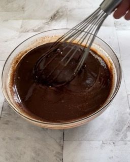 Una ciotola di salsa al cioccolato con una frusta dentro