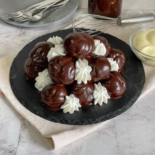 Un piatto nero guarnito con palline di cioccolato e panna montata