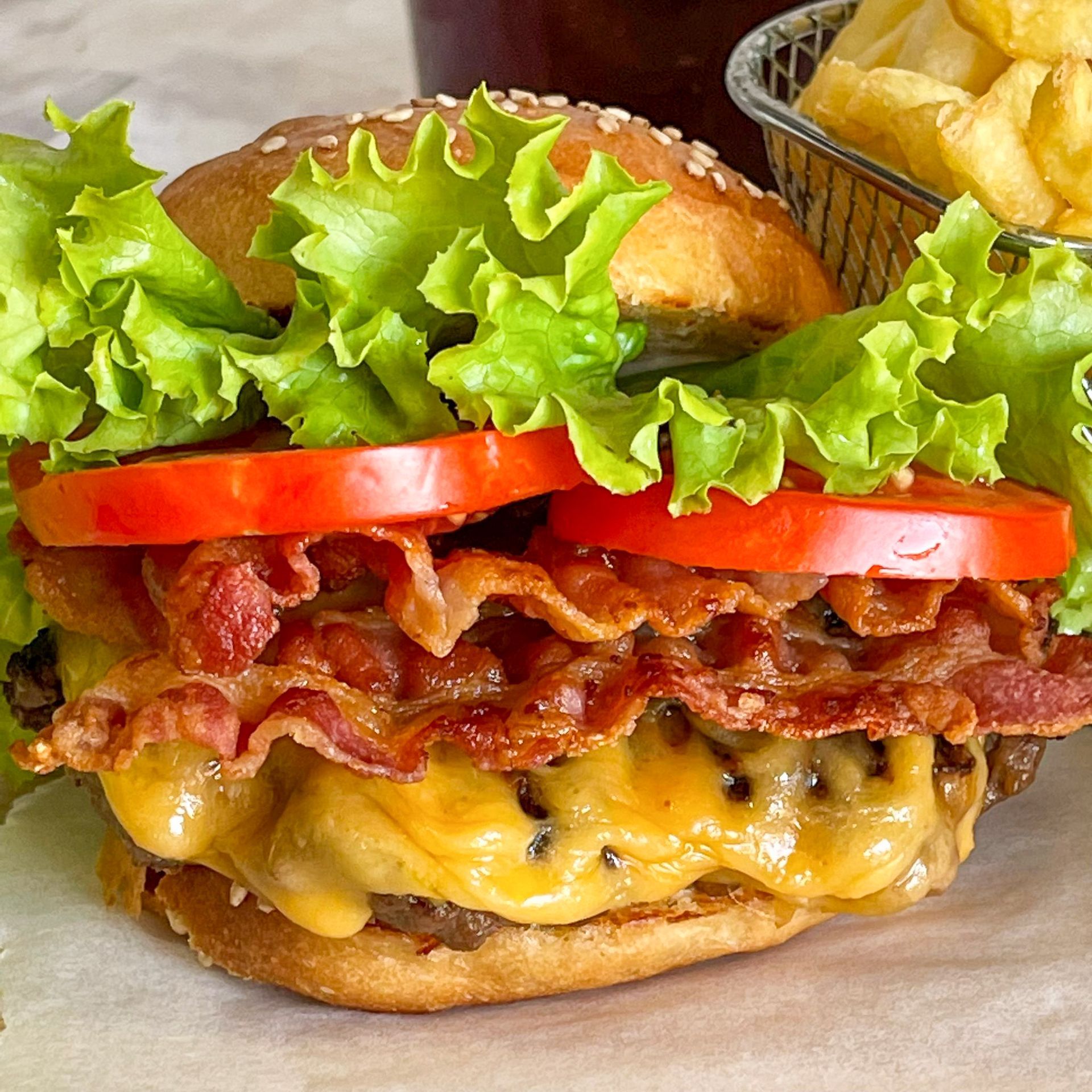Un primo piano di un hamburger con lattuga, pomodoro e pancetta