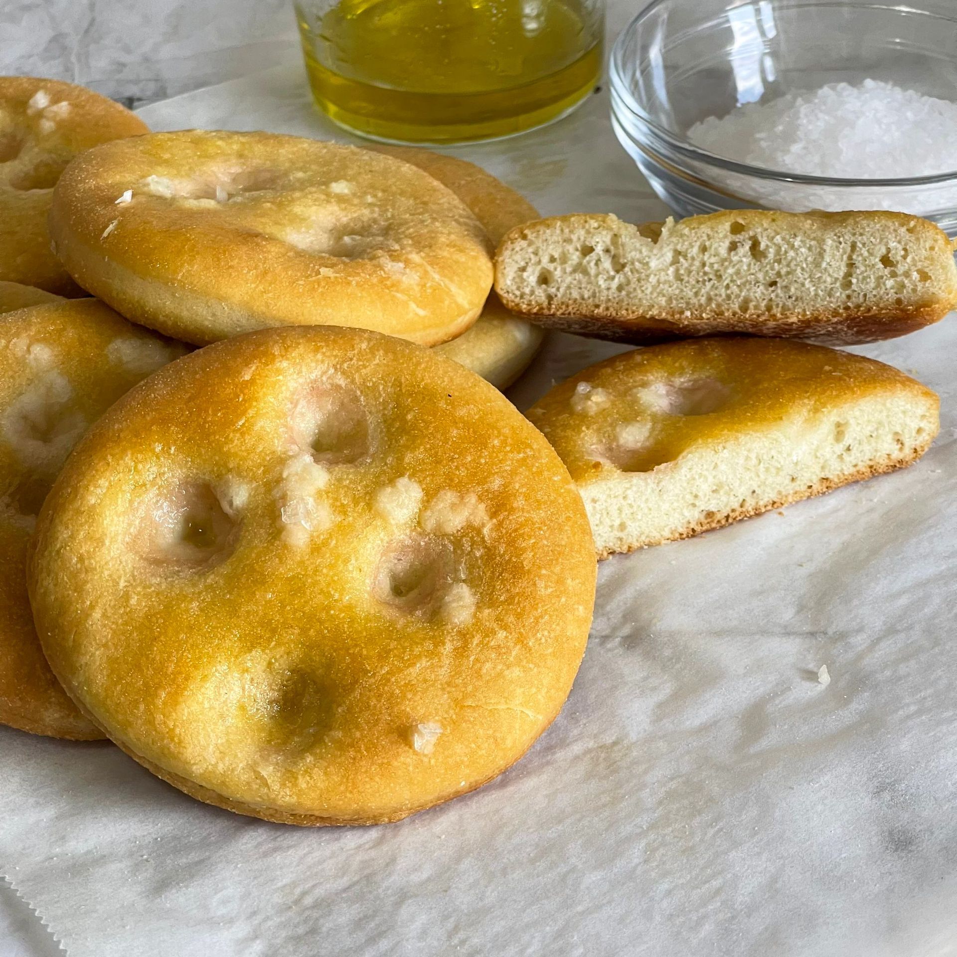 Un mucchio di pane è appoggiato su un tavolo accanto a una ciotola di sale.