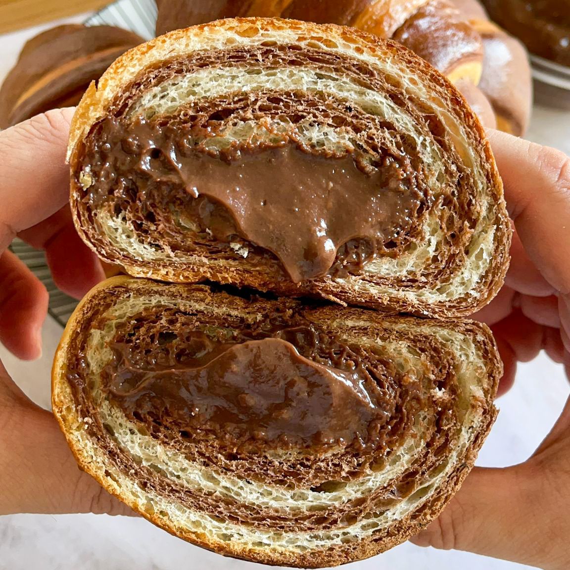 Una persona tiene in mano un pezzo di pane al cioccolato tagliato a metà.