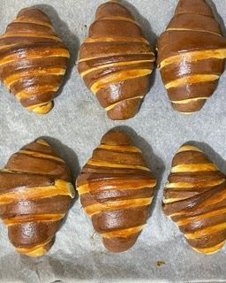 Sei croissant sono appoggiati su un pezzo di carta oleata
