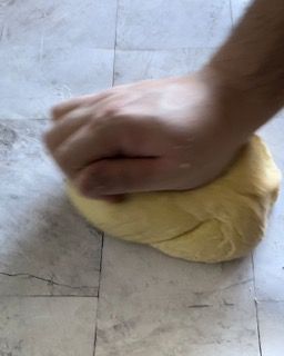 Una persona sta impastando una palla di pasta su un pavimento piastrellato.
