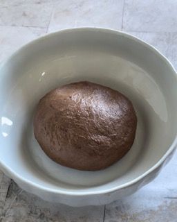 Una ciotola bianca piena di una sostanza marrone su un tavolo.