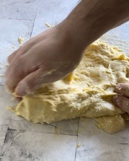 Una persona sta impastando un pezzo di pasta su un tagliere.