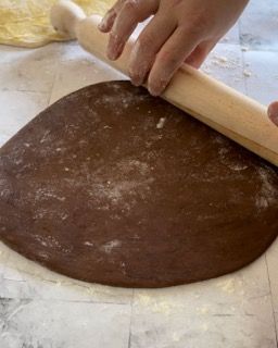 Una persona sta stendendo un pezzo di pasta al cioccolato con un mattarello.
