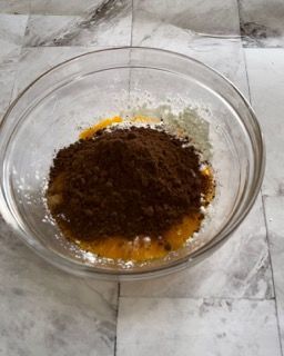 Una ciotola di vetro piena di polvere marrone e liquido giallo