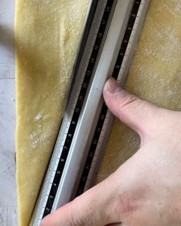 Una persona sta misurando un pezzo di pasta con un righello