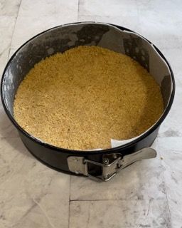 Una tortiera piena di briciole è appoggiata su un pavimento piastrellato