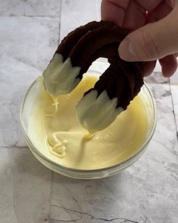 Una persona sta immergendo una ciambella al cioccolato in una ciotola di salsa