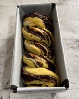 Posizionamento del babka intrecciato nello stampo da plumcake.
