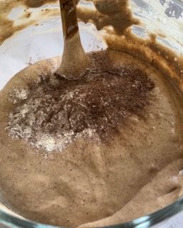 Primo piano di una ciotola contenente un liquido marrone con un cucchiaio dentro.