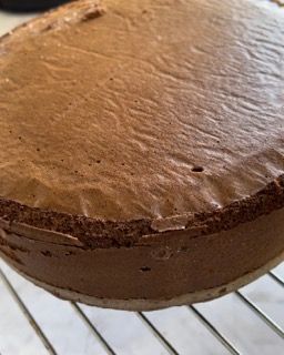 Una torta al cioccolato è appoggiata su una griglia di raffreddamento.